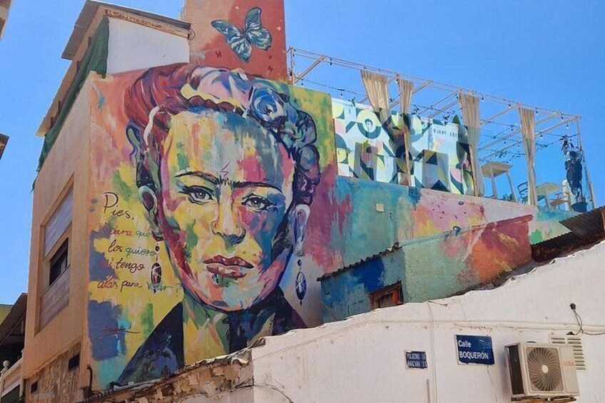 A colorful mural on a building with a butterfly and text. 3