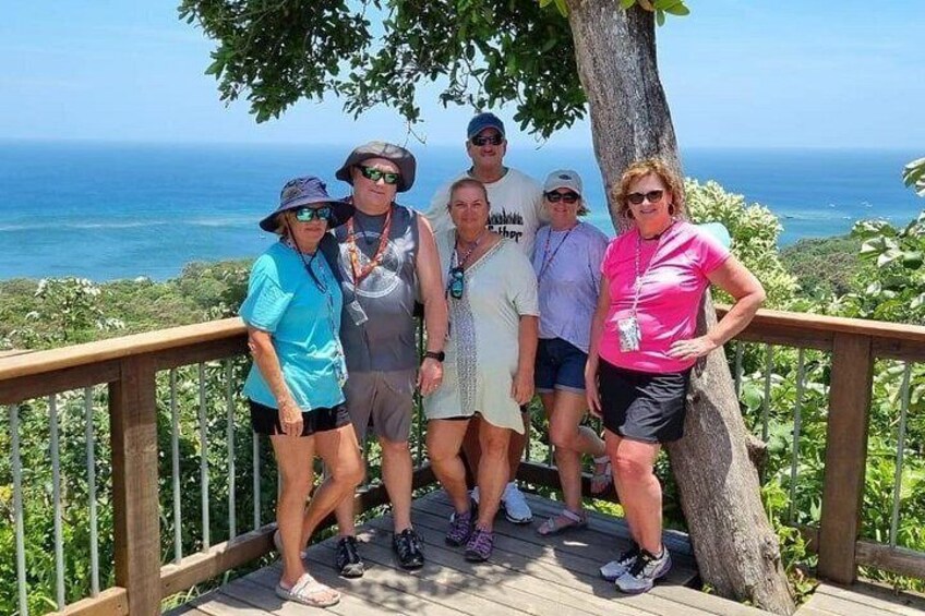 A group of people on a wooden deck overlooking a coastal landscape. 2