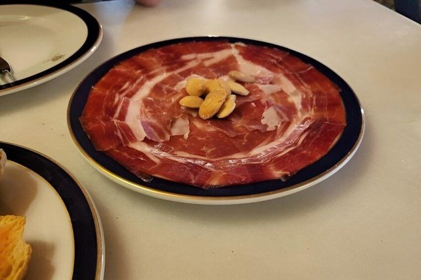 Un plato de carne curada en lonchas con almendras sobre una mesa. 4
