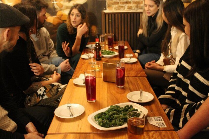 Un grupo de personas sentadas alrededor de una mesa de madera con platos de comida y bebidas. 2