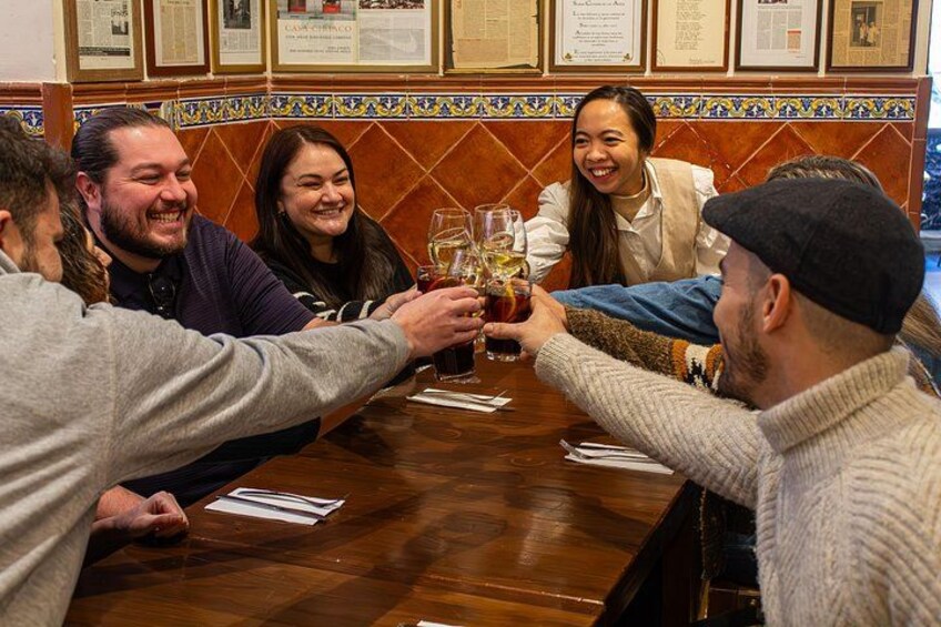 Un grupo de personas brindando con bebidas alrededor de una mesa de madera en un restaurante con paredes de azulejos. 5
