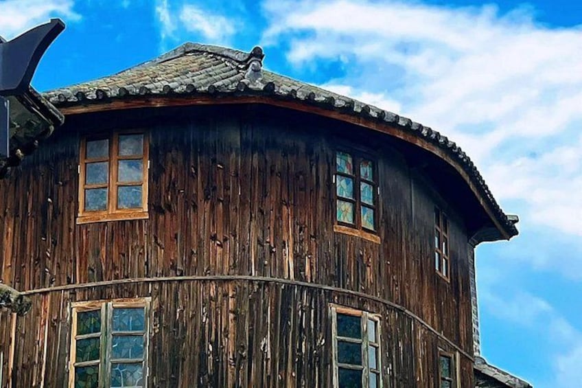 A wooden building with a curved roof and multiple windows. 1