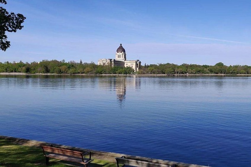 A calm lake with a large building featuring a dome in the background. 2