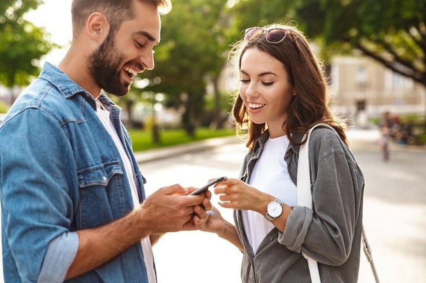 Two people standing outdoors, one holding a smartphone. 3
