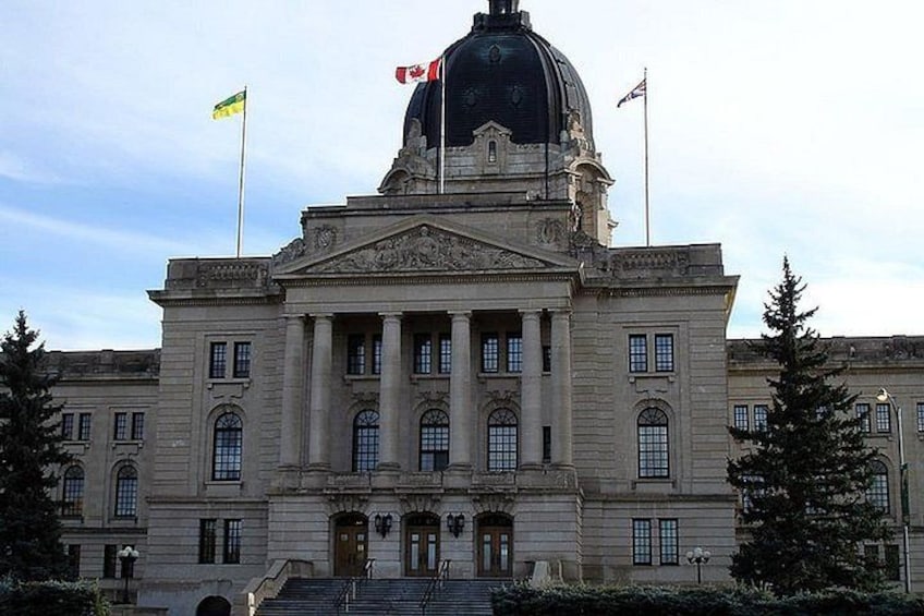 A large neoclassical building with a prominent dome and columns, surrounded by trees and flags. 2