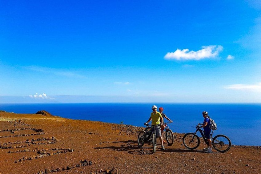 Två personer på cyklar i ett stenigt landskap med fri utsikt över havet. 4