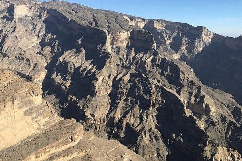A rugged mountain landscape with layered rock formations and a clear sky. 5