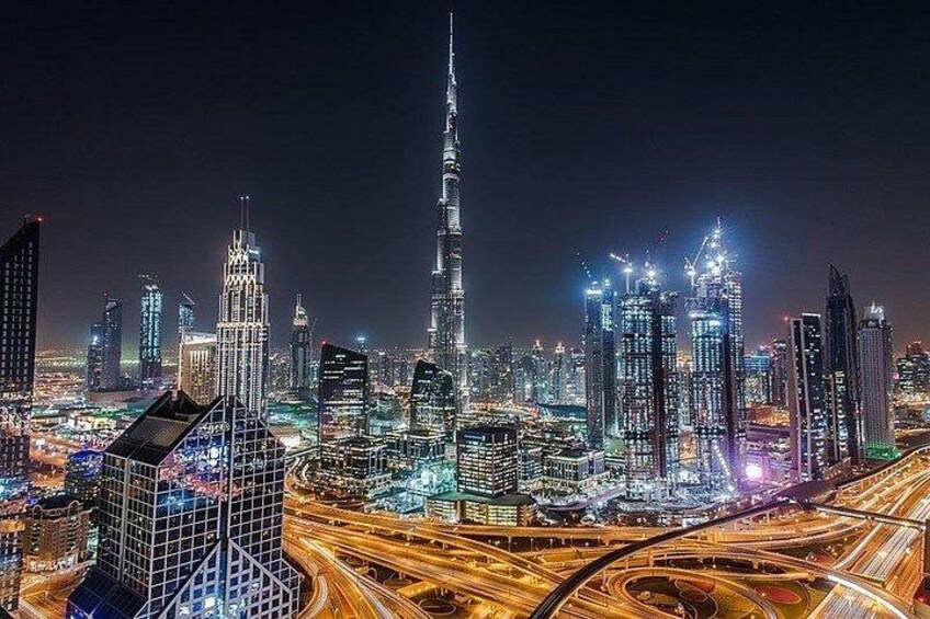 A cityscape at night with illuminated skyscrapers and a prominent tower. 1