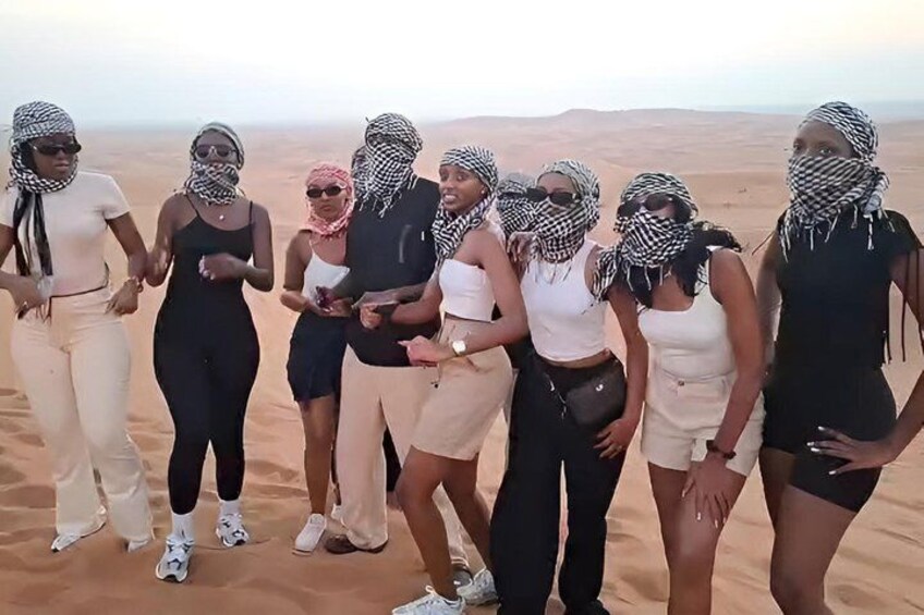 En gruppe mennesker står i en ørken med sandklitter i baggrunden. 5