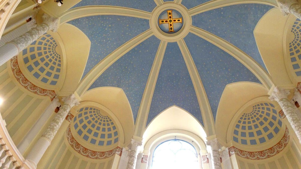 A church interior with a starry dome ceiling, a central cross, and ornate columns. 2