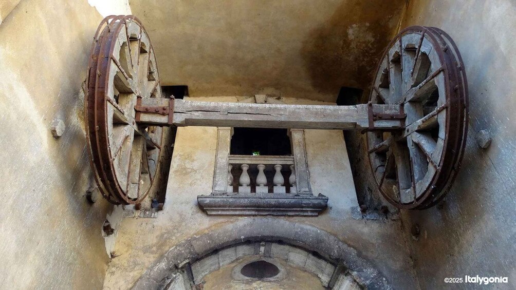 An old, rusted wheel mechanism with a small window and balustrade. 3