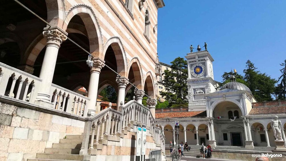 A historic building with arches and columns, a clock tower, and a dome. 1