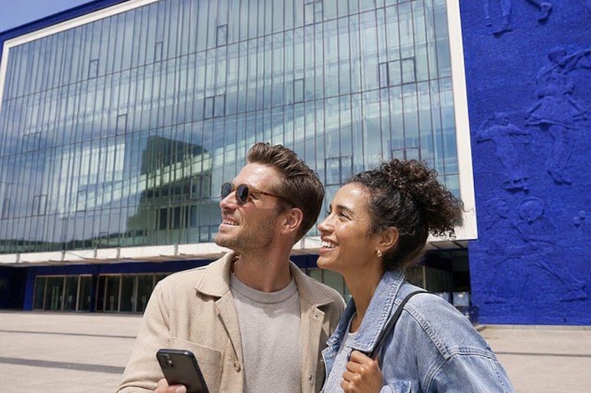 Two people standing in front of a modern building with a blue facade. 2