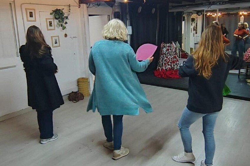 Tre personer i ett rum med en scen, en dörr med bilder på och en papperskorg. 1
