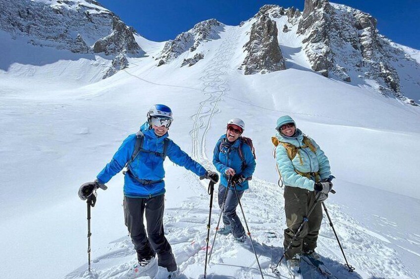 Three skiers on a snowy mountain with rocky peaks in the background. 1