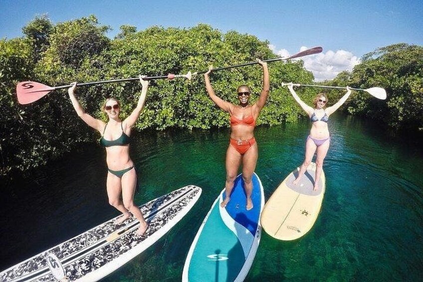 Three people paddleboarding on a calm river surrounded by lush greenery. 2