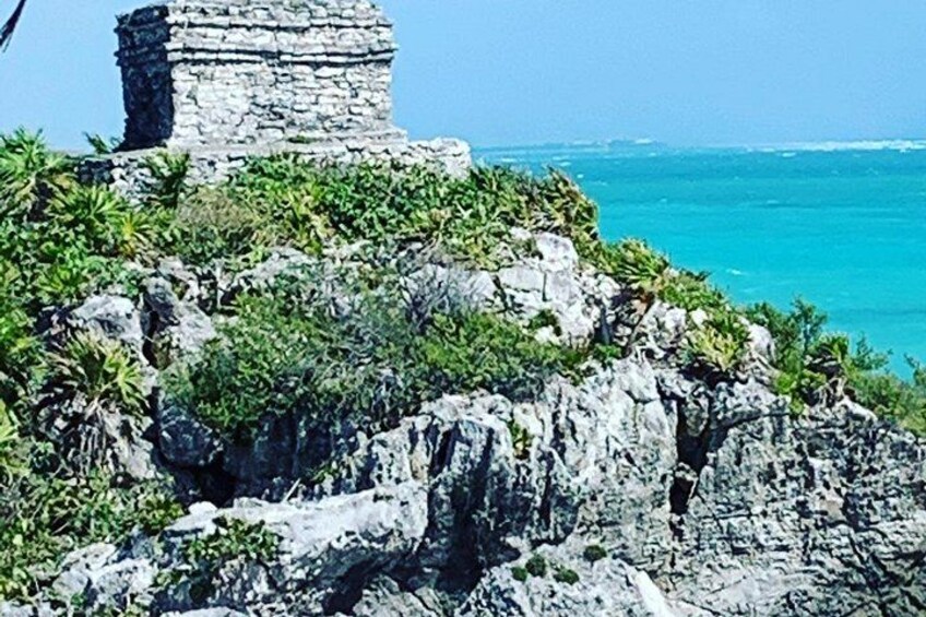 A stone structure on a rocky cliff overlooking turquoise waters. 5