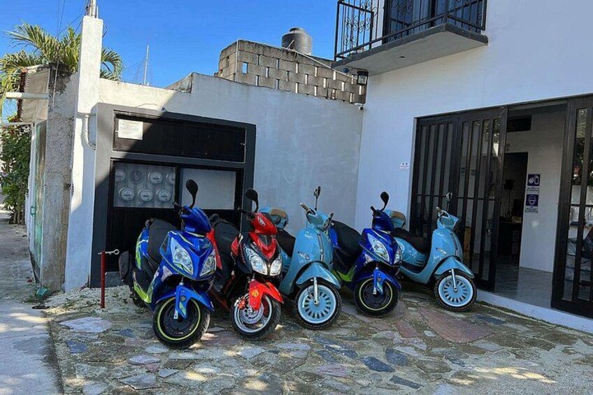 A row of scooters parked in front of a building with a garage. 4