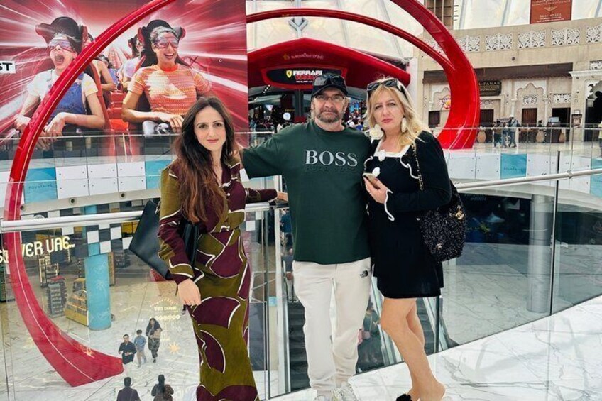 Un centro commerciale con una grande struttura circolare rossa, un negozio Ferrari e una persona che indossa una maglietta 'BOSS'. 3