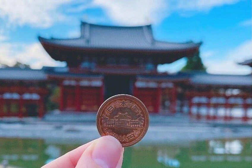 A hand holding a coin in front of a traditional building. 5