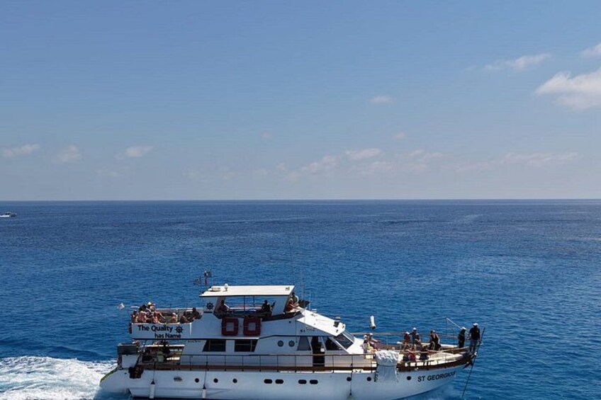 Ein weißes Boot mit der Aufschrift 'The Queen of the Caribbean', das auf einem blauen Ozean fährt. 2