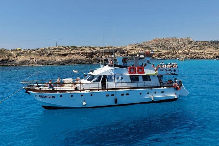 Ein weißes Boot namens ST GEORGIOS auf klarem, blauem Wasser, im Hintergrund felsige Hügel. 5