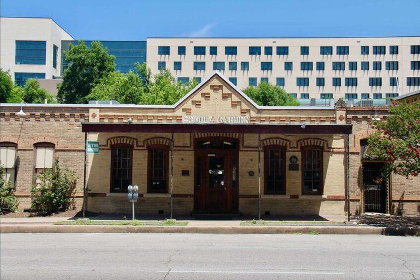 A historic building with a classic facade, a prominent entrance, and a sign reading "SCHOOL GARDEN". 4