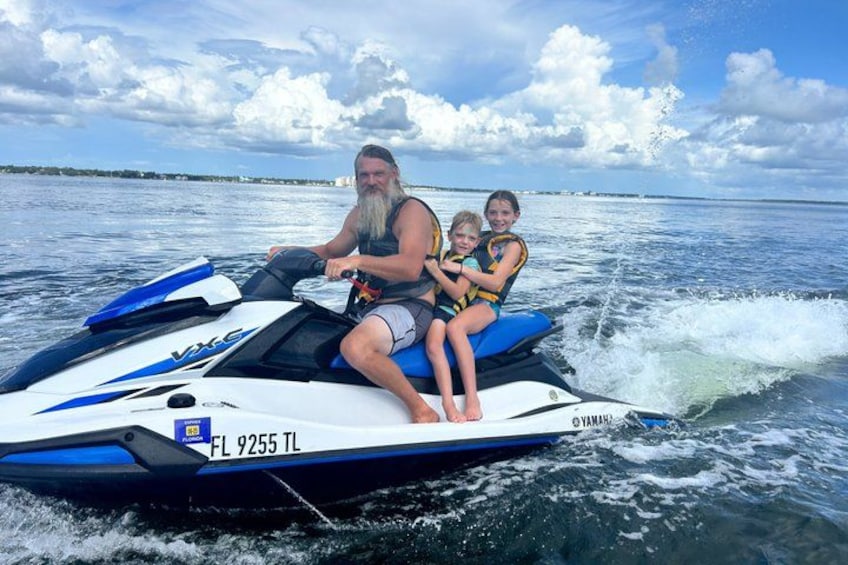 A person riding a jet ski with two children on board. 2