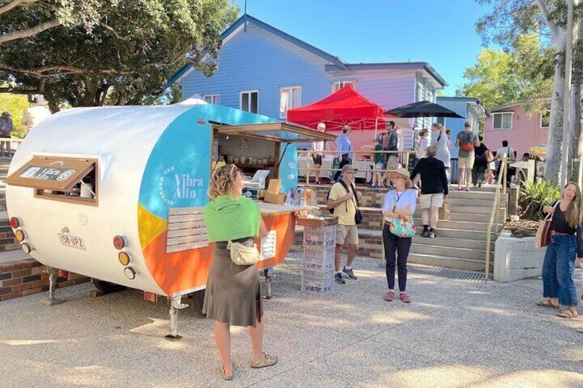 A food truck with a colorful design parked on a paved area with people around it. 1