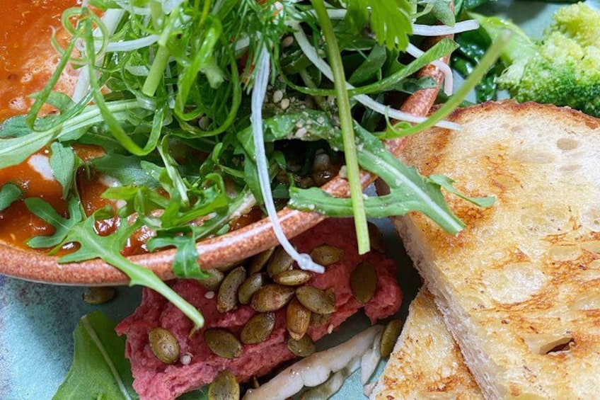 A sandwich with arugula, capers, and a slice of toasted bread. 2