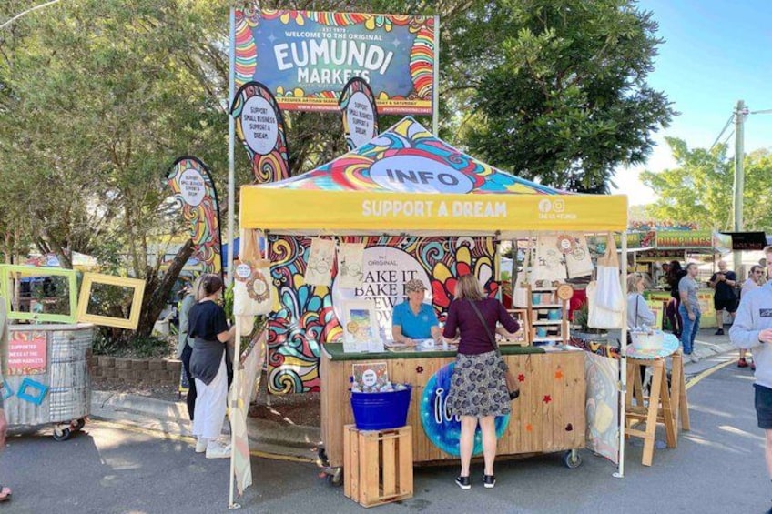 A colorful market stall with a sign that reads 'EUMUND! MARKETS' and 'INFO SUPPORT A DREAM.' 4