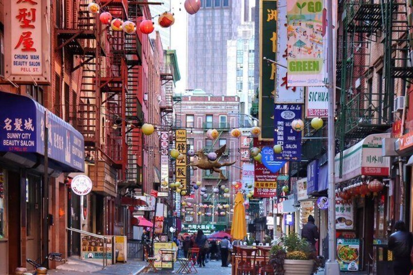 Une rue animée bordée de boutiques et de restaurants de toutes sortes, agrémentée de lanternes suspendues et d’enseignes en langue étrangère. 2