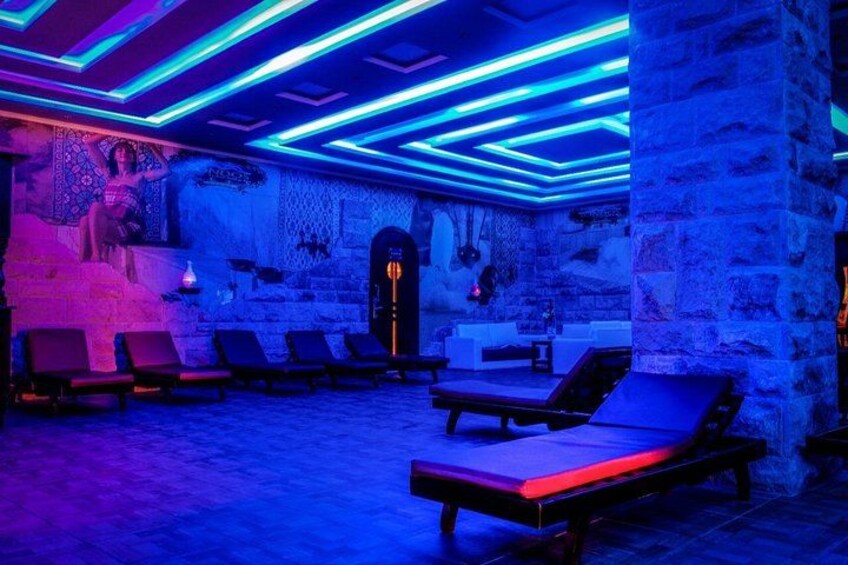 A spa with stone walls, blue lighting, and sun loungers. 5