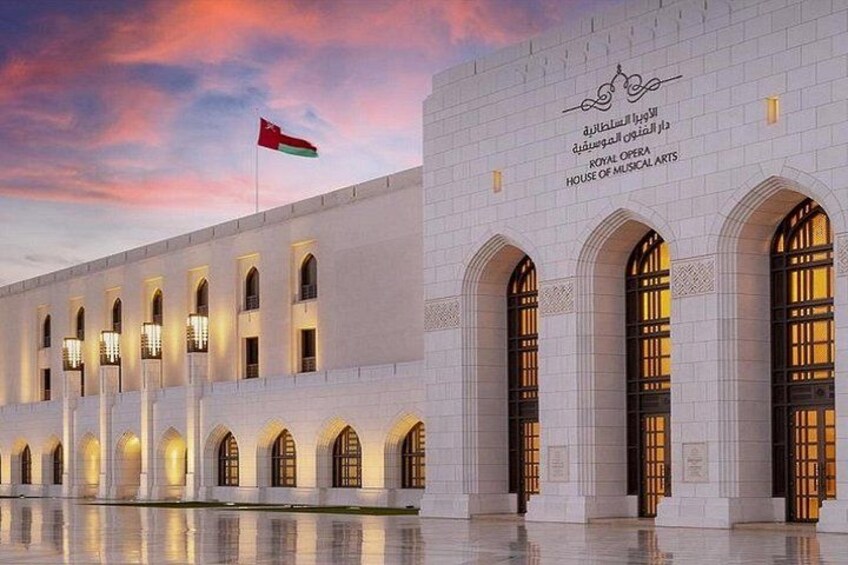 A large white building with arched windows and a flag on top. 1