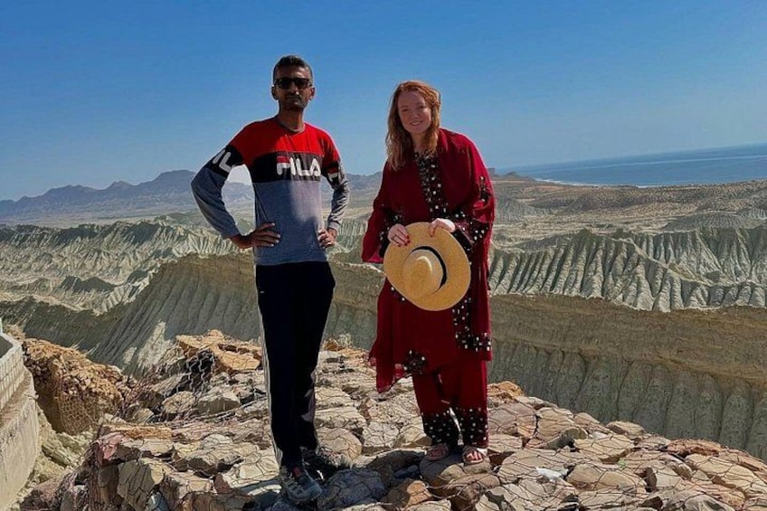Two people standing on a rocky outcrop with a vast landscape in the background. 5