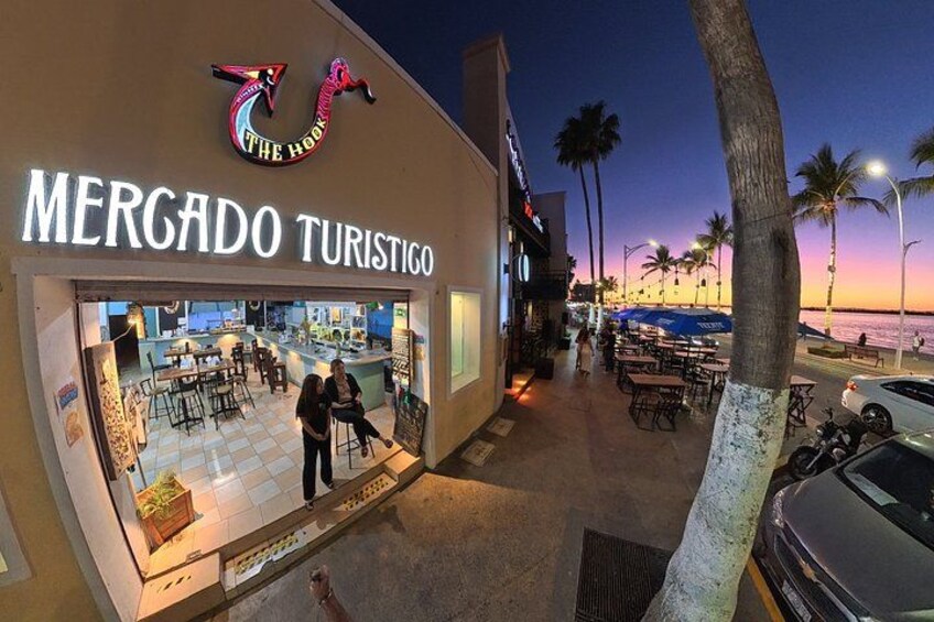 A beachfront restaurant named 'The Hook' with outdoor seating and palm trees. 2