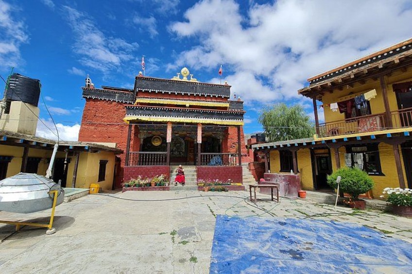 A traditional building with a red facade and a golden roof, surrounded by smaller structures. 5