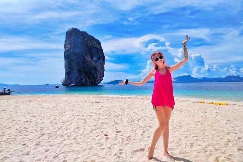 Una persona su una spiaggia sabbiosa, con una grande formazione rocciosa sullo sfondo. 4