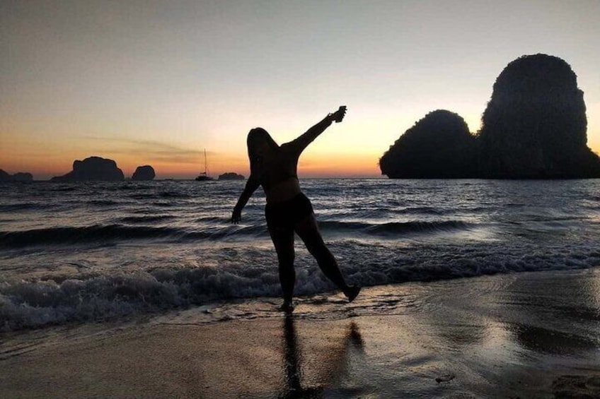 Una persona corre lungo una spiaggia al tramonto, con le onde e formazioni rocciose sullo sfondo. 3