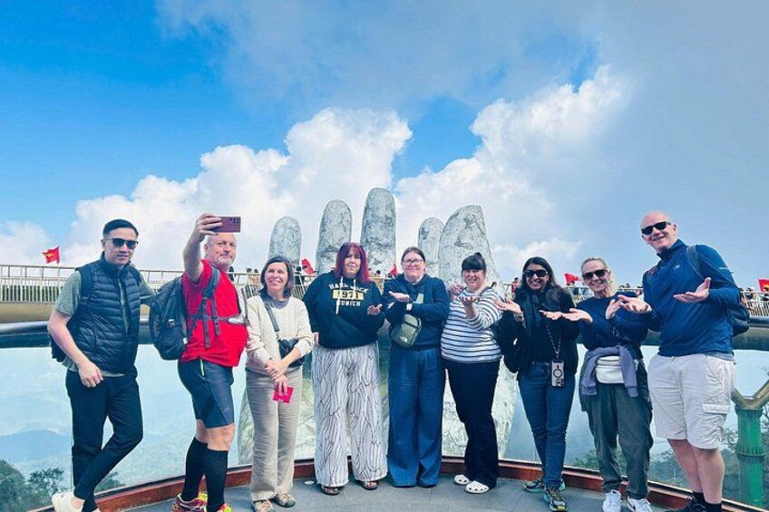 A group of people standing on a bridge with a scenic view of mountains and clouds in the background. 5
