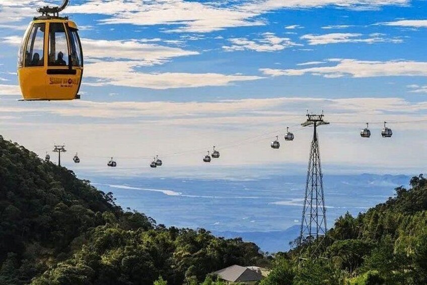 A cable car system with multiple gondolas in operation, a transmission tower, and a mountainous landscape with dense vegetation. 4