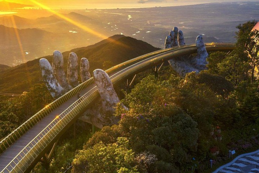 A bridge with a unique hand-shaped design, surrounded by lush greenery and mountains in the background. 2