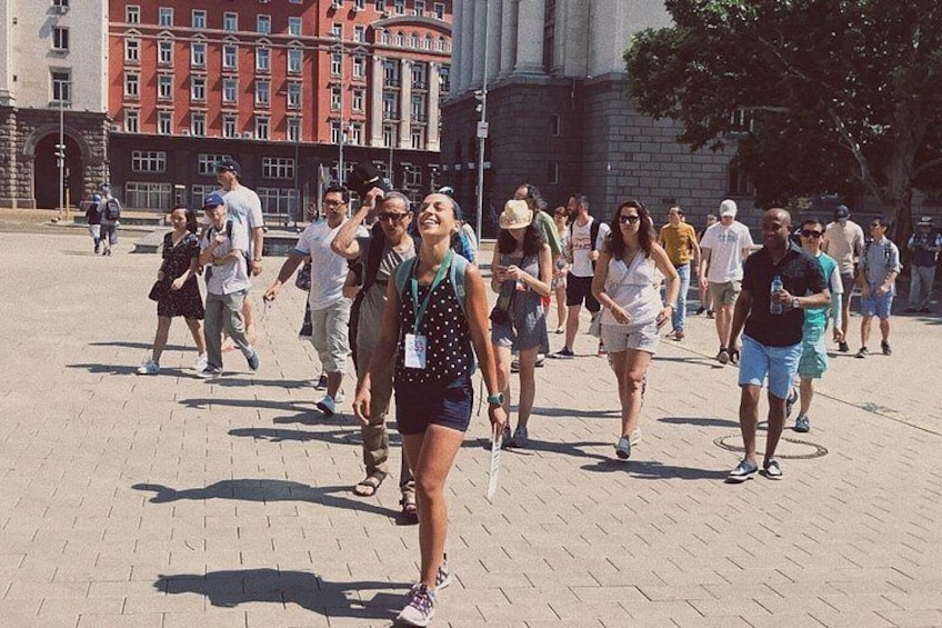 Un grupo de personas caminando sobre una superficie pavimentada con edificios al fondo. 2