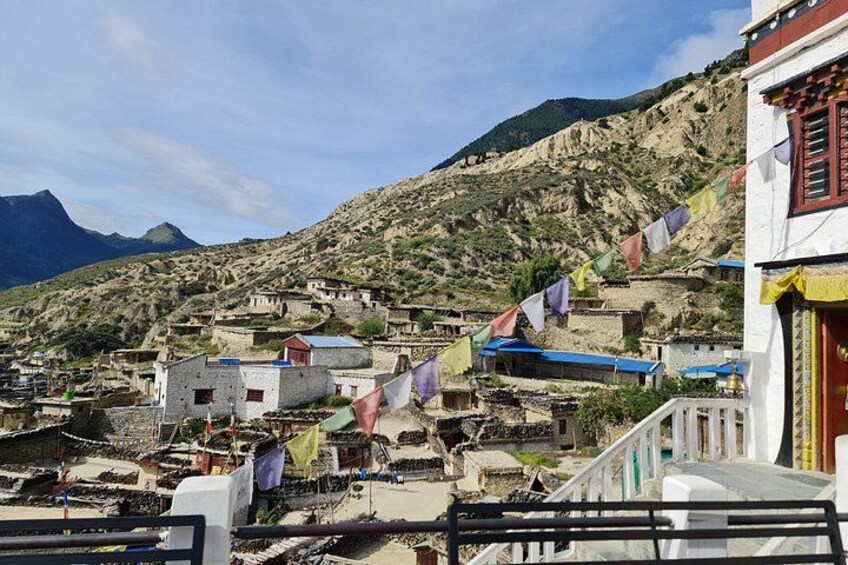 Un pueblo montañoso con casas escalonadas y coloridas banderas de oración. 5