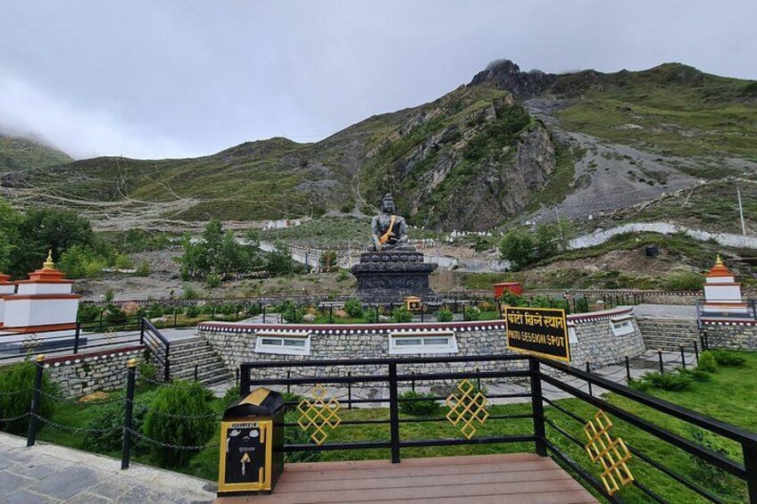 Un paisaje montañoso con una estatua, un templo y un cartel. 1