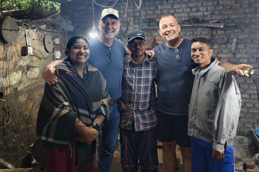 A group of people standing in a rustic, brick-walled room with exposed pipes and a hanging light fixture. 2