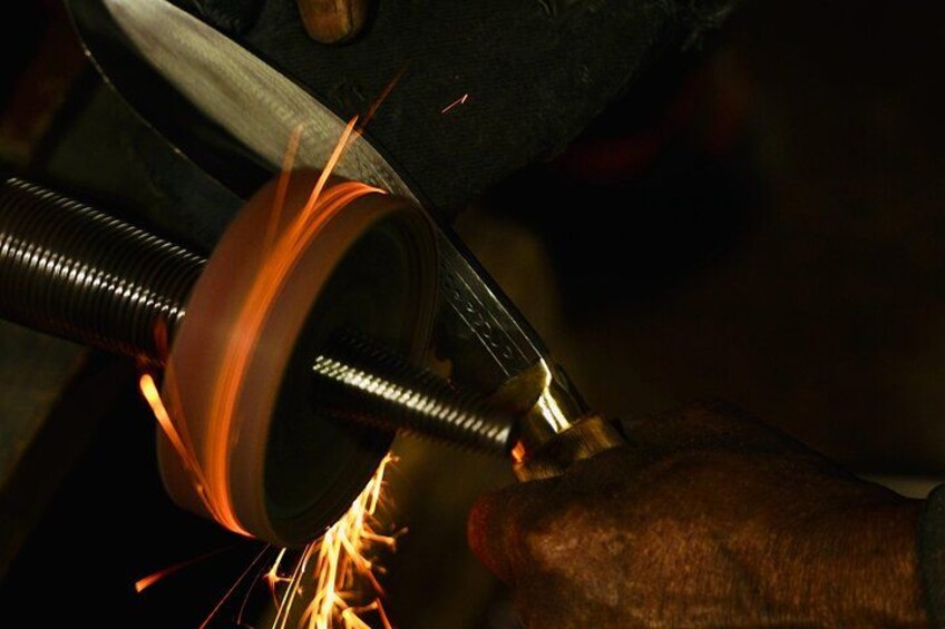 A close-up of a grinding tool with sparks flying, a metal rod, and a hand wearing a glove. 3