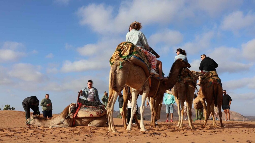 A group of people riding camels in a desert landscape. 2
