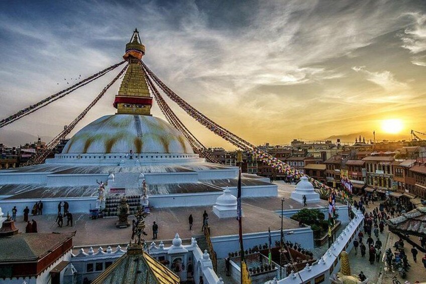 A large white stupa with a golden spire, surrounded by a crowd of people. 3