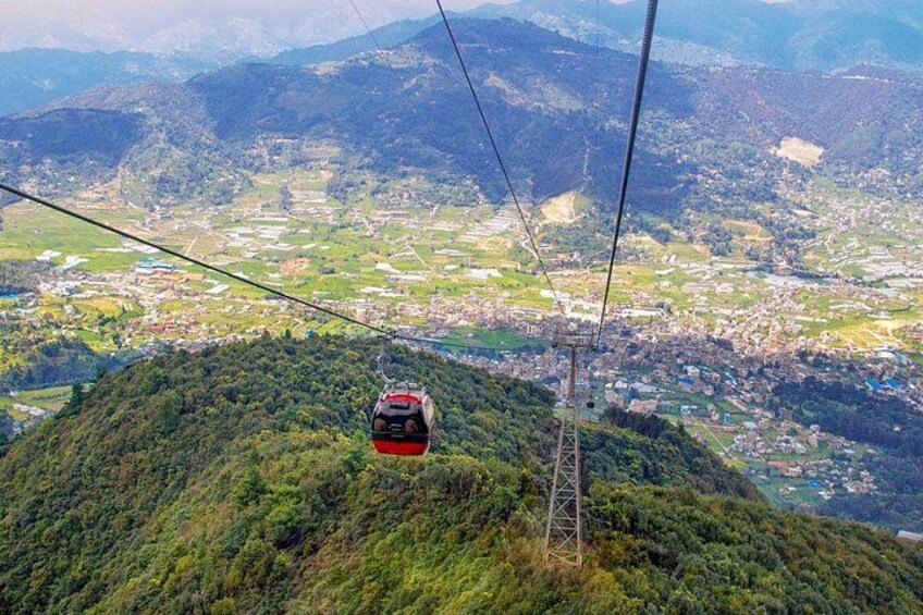 A cable car moving over a mountainous landscape with a town below. 1